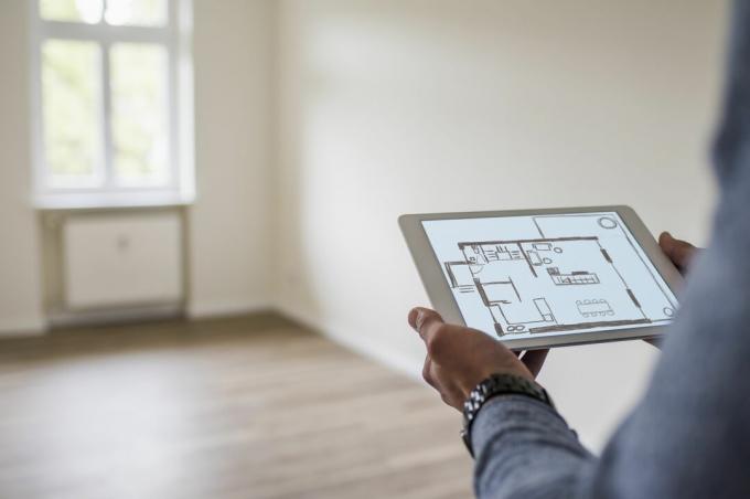 Mens in de nieuwe tablet die van de huisholding een digitaal vloerplan toont