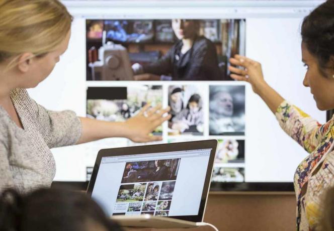 Twee vrouwen bekijken een website op laptop en groot scherm