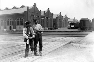 Twee militairen staan ​​naast het Pullman-gebouw en trainen auto's met gesloten armen en een fles sterke drank tijdens de 1894 Chicago Pullman Strike