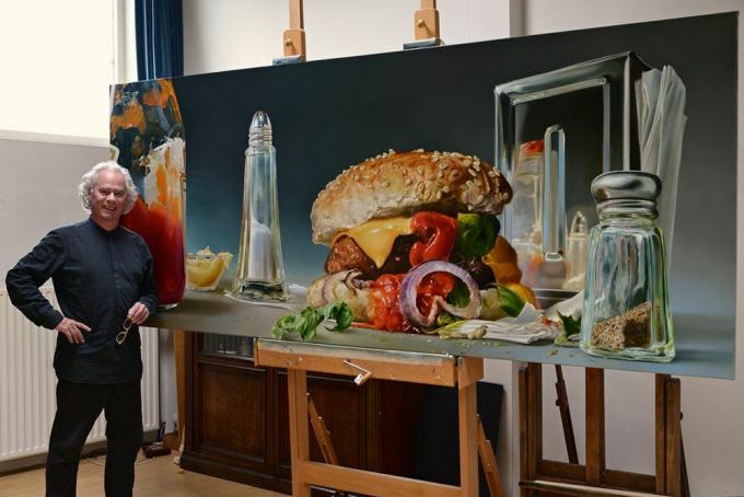 Man staat met oversized afbeelding van een hamburger en zout en peper shakers.