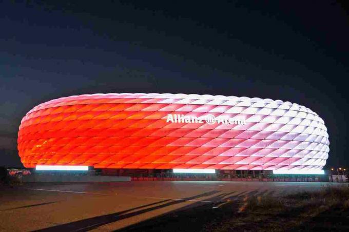 Overdag wit, de gebeeldhouwde buitenkant van de Allianz Arena licht 's nachts rood op