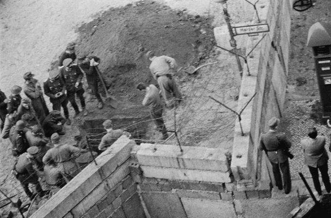 Een groep Oost-Duitse soldaten onderzoekt een tunnel die onder de Berlijnse muur is gegraven.