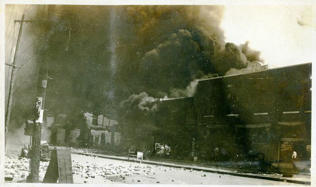 Beschadigde eigendommen en rook afkomstig van gebouwen na de Tulsa Race Massacre, Tulsa, Oklahoma, juni 1921.