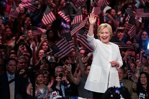 Hillary Clinton zwaait voor een menigte mensen die met Amerikaanse vlaggen zwaaien