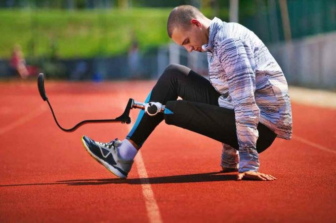 Jonge man met koolstofvezel prothetische ledemaat uitoefenen op een zonnige dag op een track