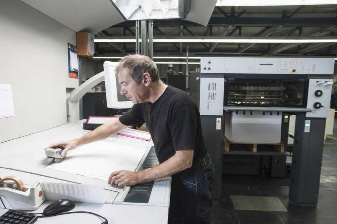 Werknemer die digitale afdrukapparatuur voorbereidt in de drukkerij