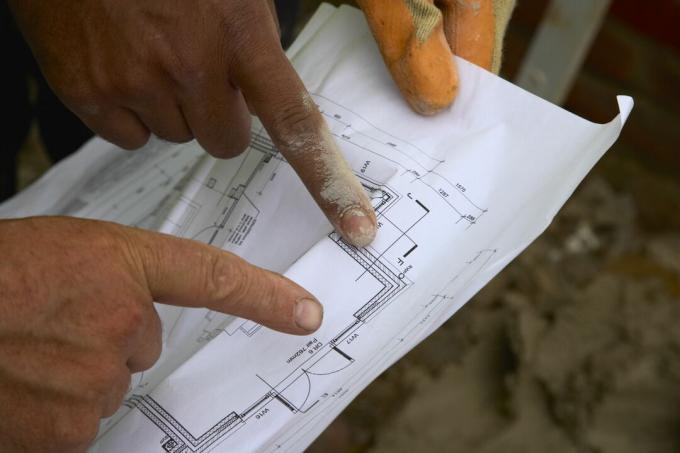 Bouwvakkers kijken naar plannen, je ziet alleen hun vingers wijzen