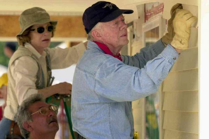 De voormalige Amerikaanse president Jimmy Carter en zijn vrouw Rosalyn bevestigen gevelbekleding aan de voorkant van een Habitat for Humanity-huis dat op 10 juni 2003 wordt gebouwd in LaGrange, Georgia.