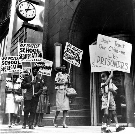 Demonstranten, waaronder een jonge jongen, pikten op voor het kantoor van een schoolbestuur uit protest tegen segregatie.