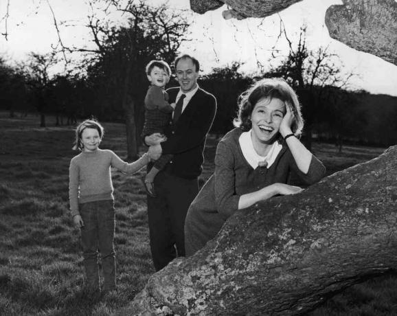 Zwart-witfoto van Roald Dahl die zijn kinderen vasthoudt; zijn vrouw Patricia Neal leunt tegen een boom