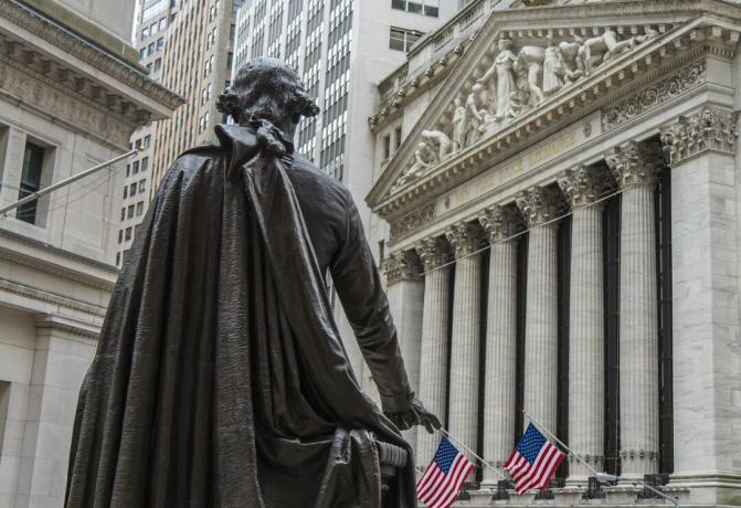 Een standbeeld van George Washington kijkt naar het gebouw van de New York Stock Exchange op Broad Street vanaf het Federal Hall National Memorial op Wall Street in New York City.