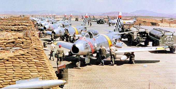 F-86 Sabres stonden opgesteld op een landingsbaan bij een muur van zandzakken.