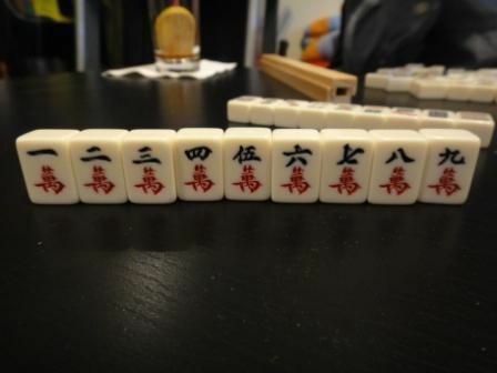 Het karakterpakket van een set Mahjong-tegels die rechtop op een tafel zitten.