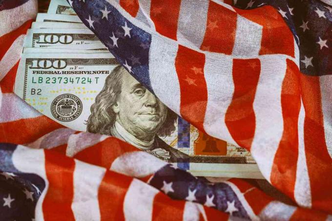 Amerikaanse vlag gewikkeld rond honderd-dollarbiljetten.