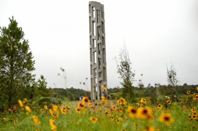 hoge, dunne stenen klokkentoren in een veld van bloemen