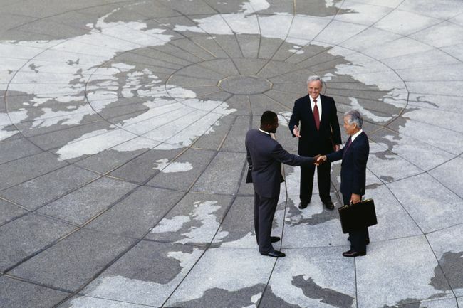  Economisch regionalisme: zakenlieden die handen schudden op de kaart van de wereld.