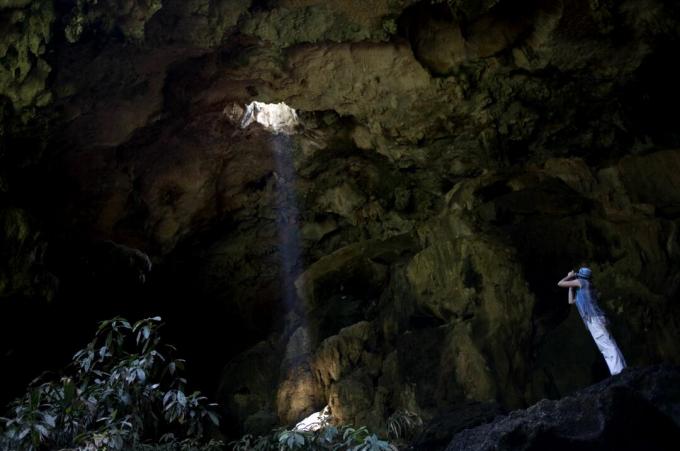 Een toerist maakt foto's bij de ingang van de Calcehtok-grot in Oxkintok, Yucatan, op het Mexicaanse schiereiland Yucatan.