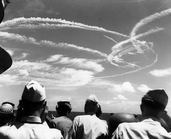 Amerikaanse matrozen die hemelwaarts kijken naar de contrails die worden gevormd door vliegtuigen die over de vloot vechten.